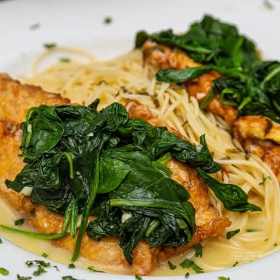 Spinach-topped cutlets and spaghetti.