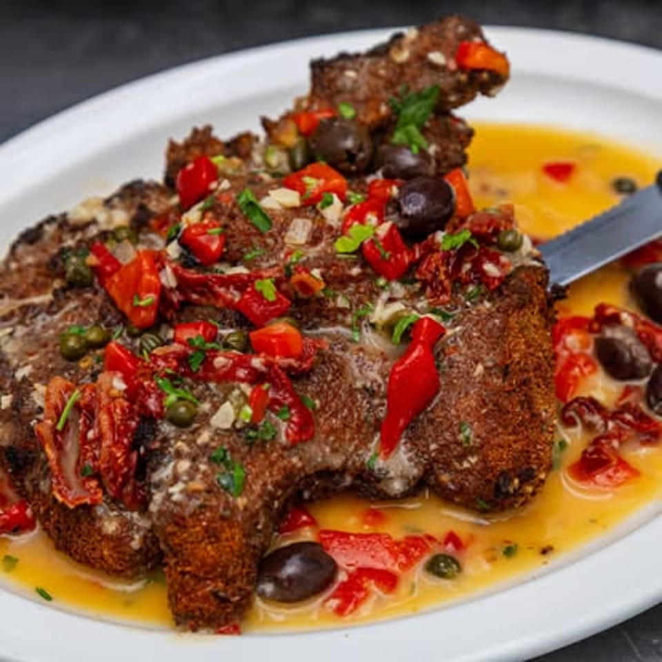Fish entree with olives, capers and diced tomatoes.