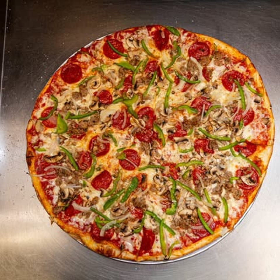 Whole pizza topped with vegetables and pepperoni.